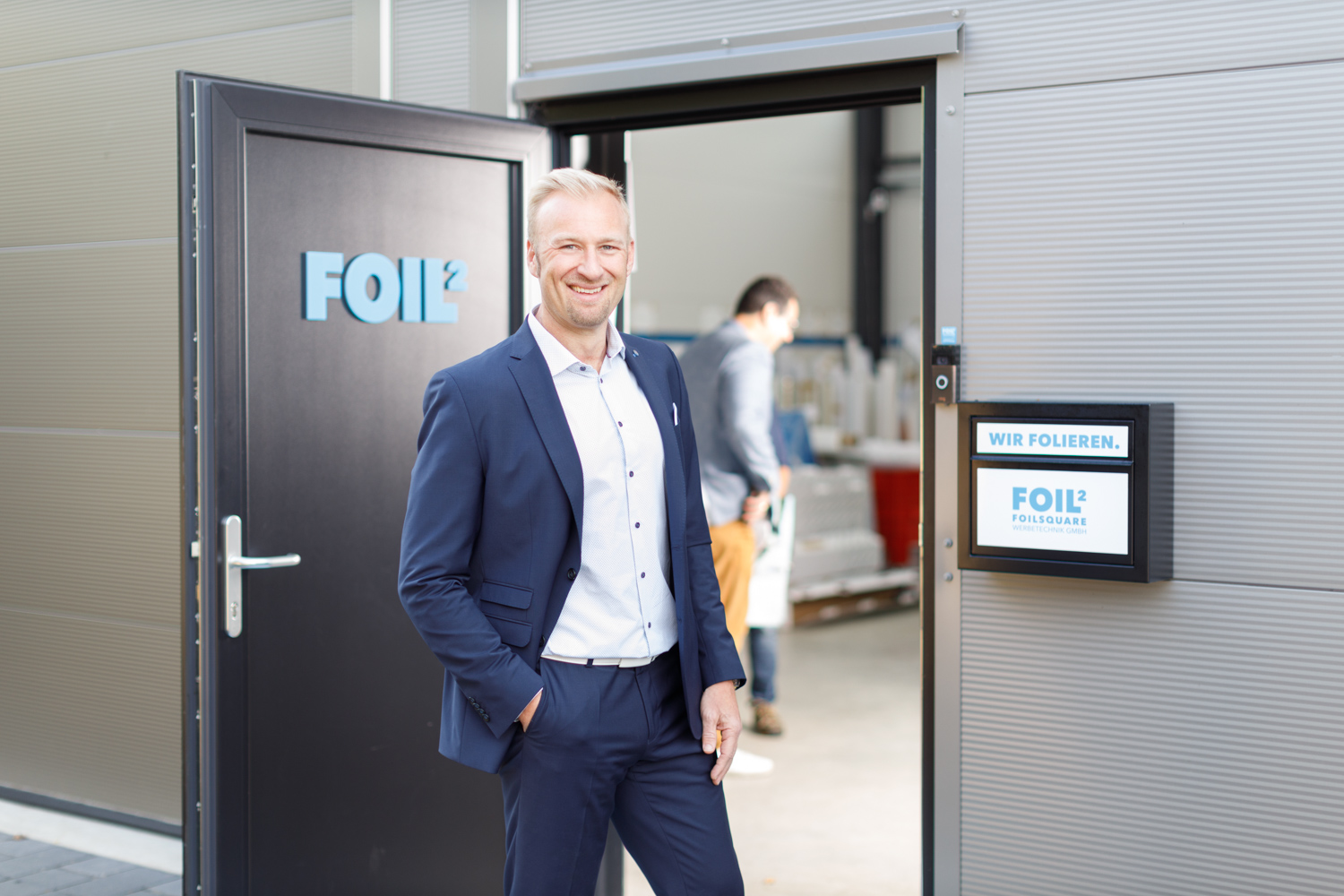 foil2Sport-LasseBrehmstehtvorFoil2SportEingangmitLächeln